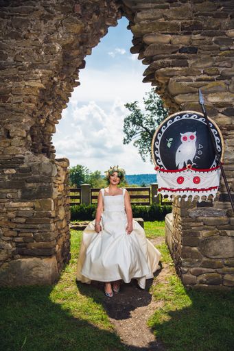 A caucasian bride wearing a white wedding dress while sitting in a park