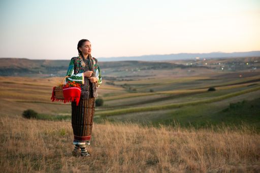 A beautiful view of a young woman with Romanian traditional clothes standing in the field