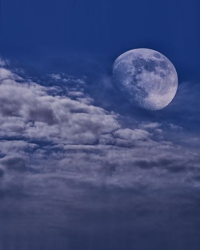 The Waxing gibbous phase of the moon on a cloudy blue sky