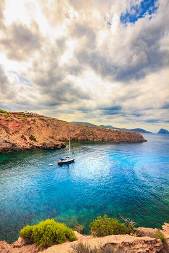 A vertical shot of a boat on the water surrounded by cliffs