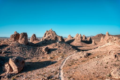 A landscape of a desert with empty road and cliffs under the clear sky