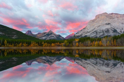 A beautiful shot of a lake water with reflection of snowy peaks and pink and blue clouds in the sky