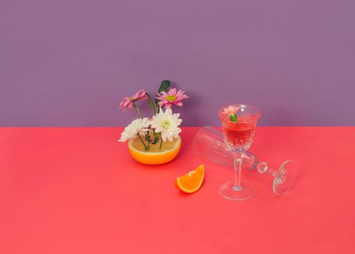 A Creative composition of white and lilac daisy flowers, fruits, and glasses for wine and champagne