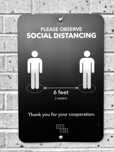 A vertical shot of a sign on the wall advocating people to keep social distancing requirements