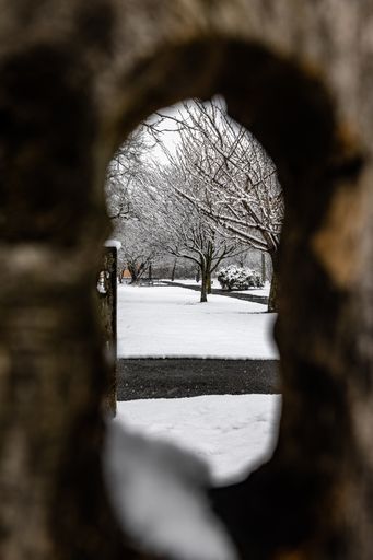 A vertical shot of a beautiful snow-covered winter landscape seen through a hole