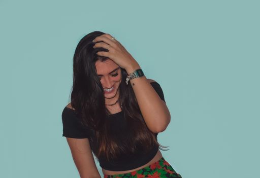 A smiling young brunette female standing in front of a blue wall - happiness concept