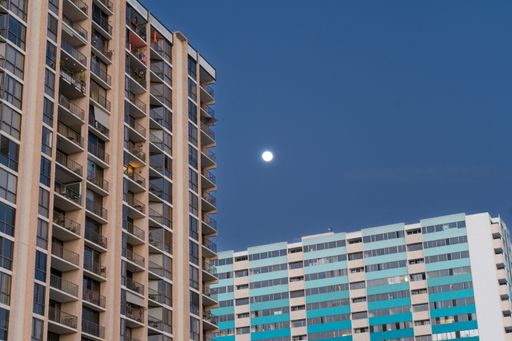 A low-angle shot of the moon over two buildings in Los Angeles, California