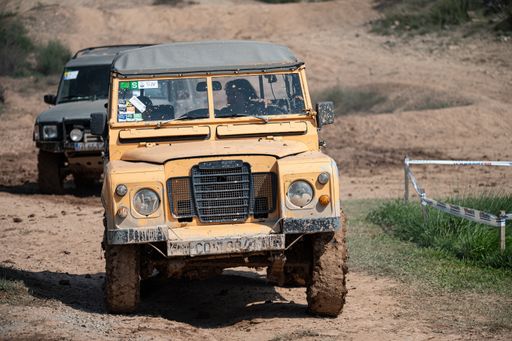 An old yellow Land Rover Santana driving on a muddy road