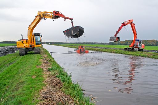 Dreding of an inland canal by two cranes, a silt pusher boat pushes the sediment towards the crane, sediment is dispursed on land.