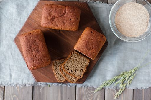 A flat lay of loaf bread on a wooden tray with yeast