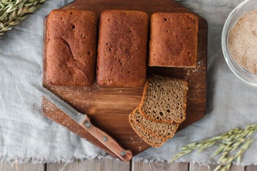 A flat lay of loaf bread on a wooden tray with yeast
