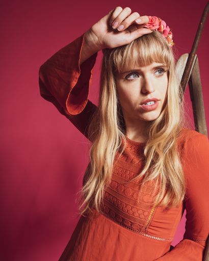 A portrait of an attractive woman with a flower crown on a pink background