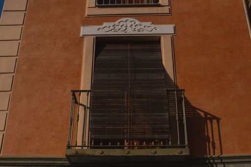 A low angle shot of an orange building small balcony
