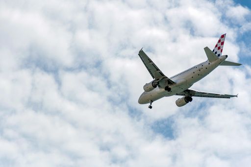 A passenger jet airplane in mid-flight against blue sky with clouds, getting ready for landing.