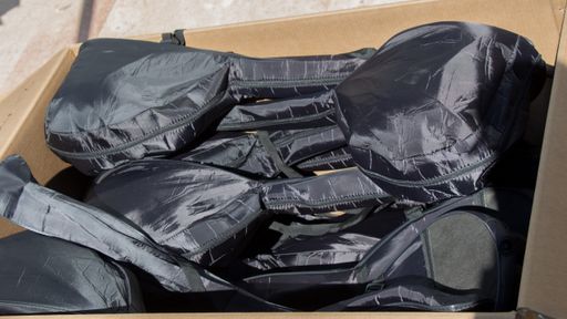 The black bags of tennis rackets in the cardboard box
