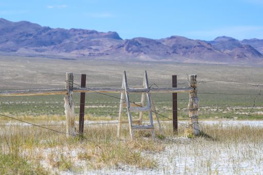 A wooden ladder crosses a cattle fence in open range in a rural area of central Nevada.