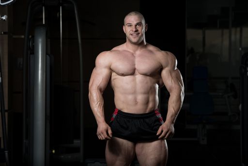Handsome Young Man Standing Strong In The Gym And Flexing Muscles - Muscular Athletic Bodybuilder Fitness Model Posing After Exercises