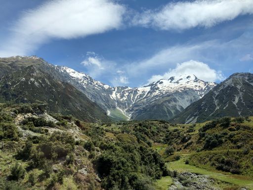 A beautiful landscape view of green trees and green ridge 
 mountains against a sunny cloudy sky