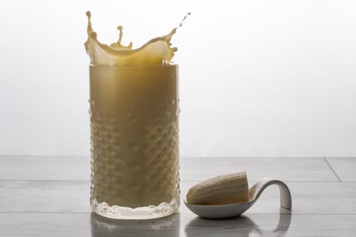 banana smoothie with fresh fruit and cookie splash effect, white background and copy-space