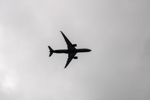 A grayscale shot of a plane flying in the sky.