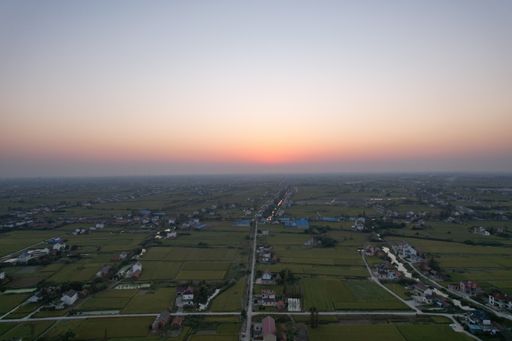 A drone shot of many country houses next to their agricultural fields.