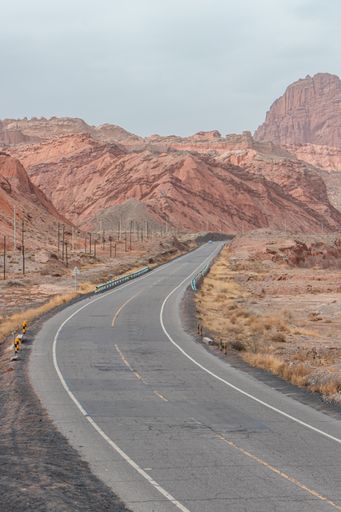 A vertical shot of a road going through rocky cliffs in the rural area of Western China