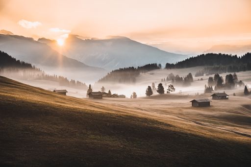 A landscape view of the Dolomites mountains under a cloudy sky during the sunrise