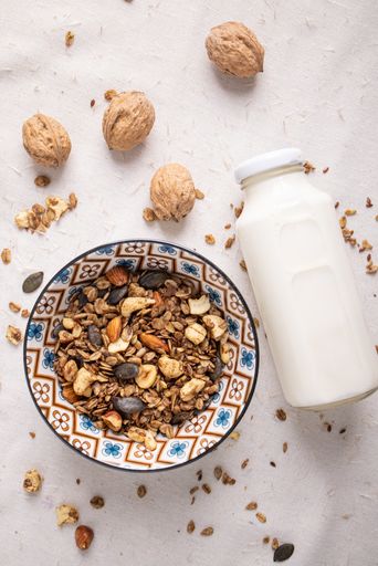 A vertical top view of delicious granolas with some fruits milk hazelnut walnut