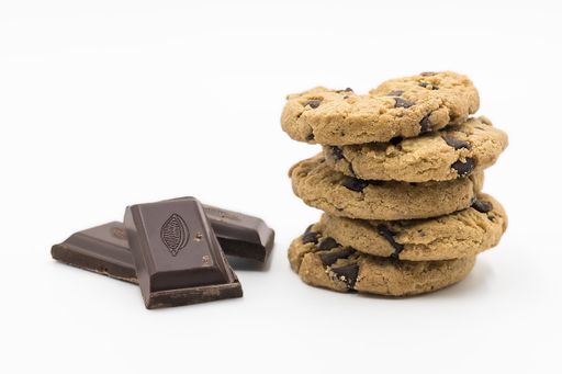 A closeup shot of dark chocolate pieces and stacked cookies isolated on a white background