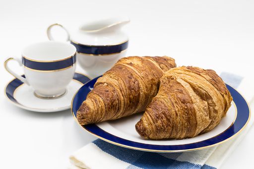 A closeup shot of two croissants on a plate and a coffee cup isolated on a white background