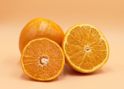 A closeup shot of a sliced orange and a full one in the background