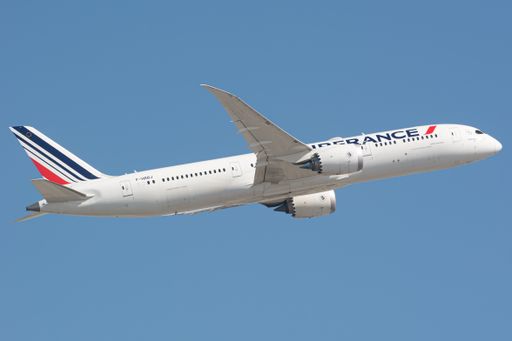 A low angle shot of the Air France Boeing 787 Dreamliner plane in the air with a blue sky background