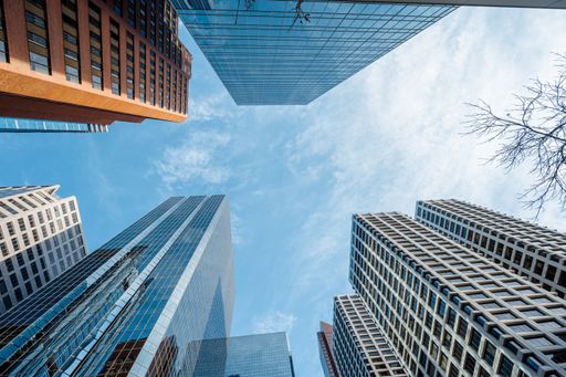 A low angle shot of high skyscrapers buildings towers in Calgary, Canada against a cloudy blue sky