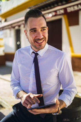 A successful young businessman in a formal outfit using a tablet