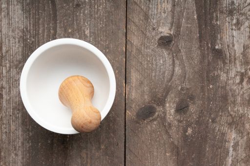 A high angle closeup shot of a mortar and pestle on a wooden surface