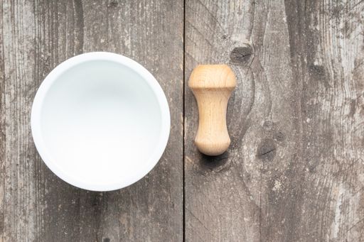 A high angle closeup shot of a mortar and pestle on a wooden surface