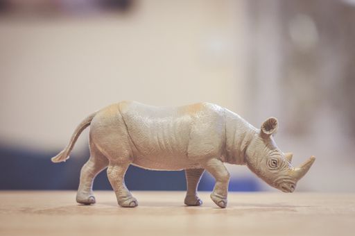 A closeup shot of a plastic rhinoceros toy on a wooden surface