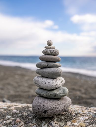 A closeup of a stack of stones on the seashore with the sea in the background
