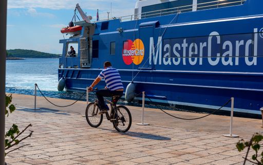 A man riding a bicycle near the advertisement Master Card most welcome in Croatia
