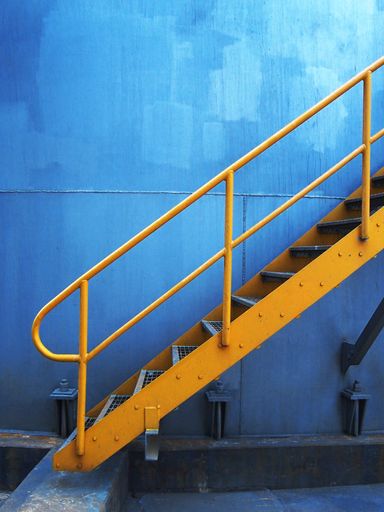 A vertical shot of a yellow metal external staircase on a blue wall background