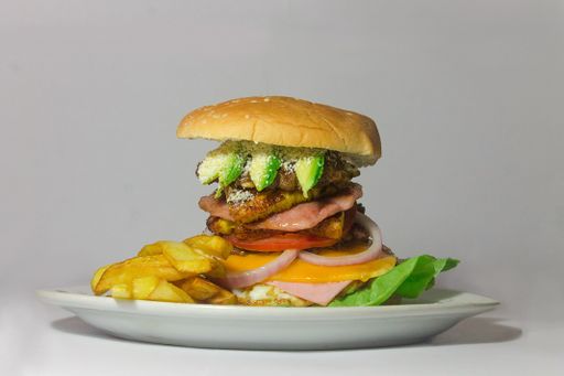 A studio shot of a juicy tall burger against a white background