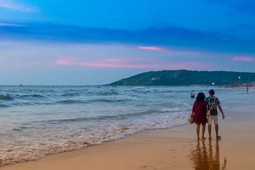 A back view of a couple walking on the Bago beach at sunset