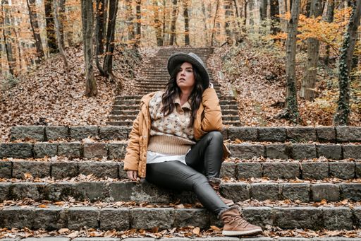 a low angle shot of a beautiful woman sitting on the stairs with hat.