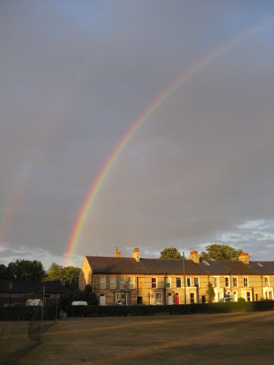 A vertical shot of assorted brown houses under a rainbow in the sky