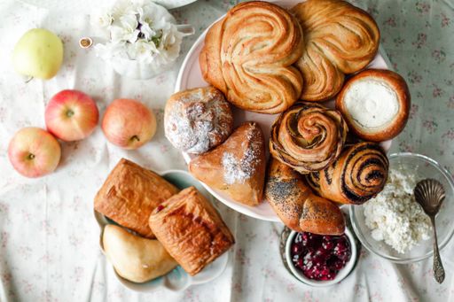 A top view of fresh baked sweet buns with sugar powder on a white plate on a table