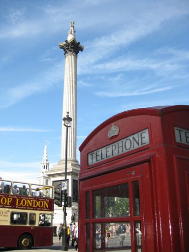 A vertical shot of a red telephone booth near the Trafalgar square under a blue sky