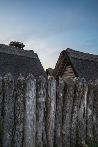 A vertical shot of the old village houses surrounded by the wooden fence during sunset