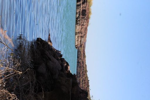 A vertical shot of lake surrounded by rocks under blue bright sky