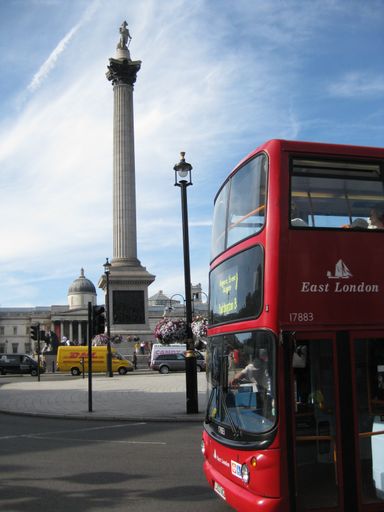 A vertical shot of a red bus near the Trafalgar square under a blue sky