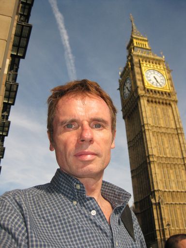 A vertical shot of a male looking at the camera with the big ben clock in the background